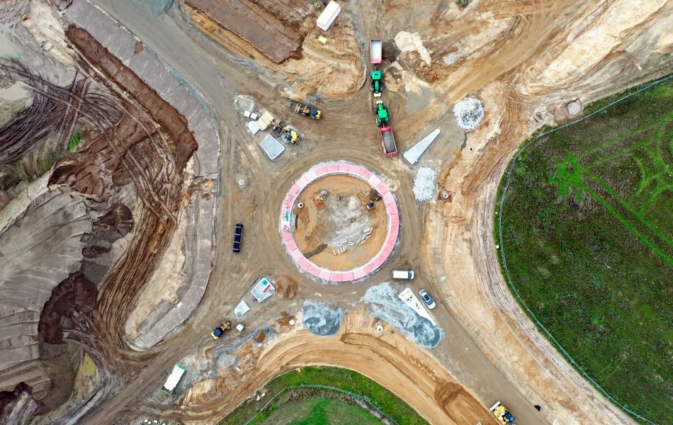 Blick von oben auf die Baustelle zur Errichtung des Kreisverkehrs an der Leeraner Straße. Die Verkehrsinsel, der innere Kreis und die äußeren Begrenzungen sind bereits angelegt. Noch besteht die Fahrbahn aus Erde.